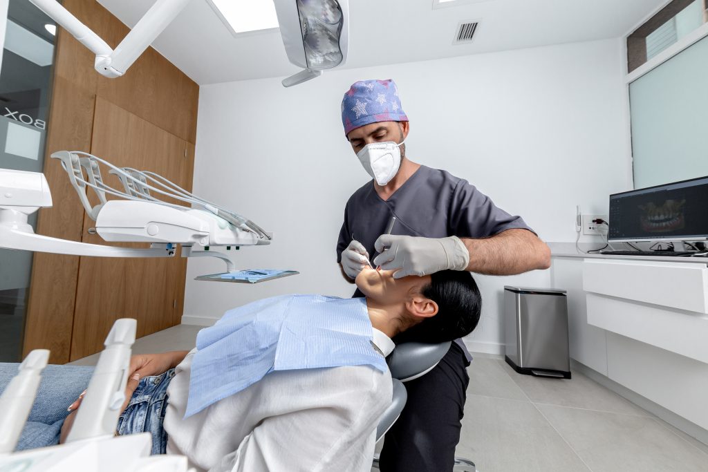 Dentist standing while examining the mouth of a patient in a dental clinic